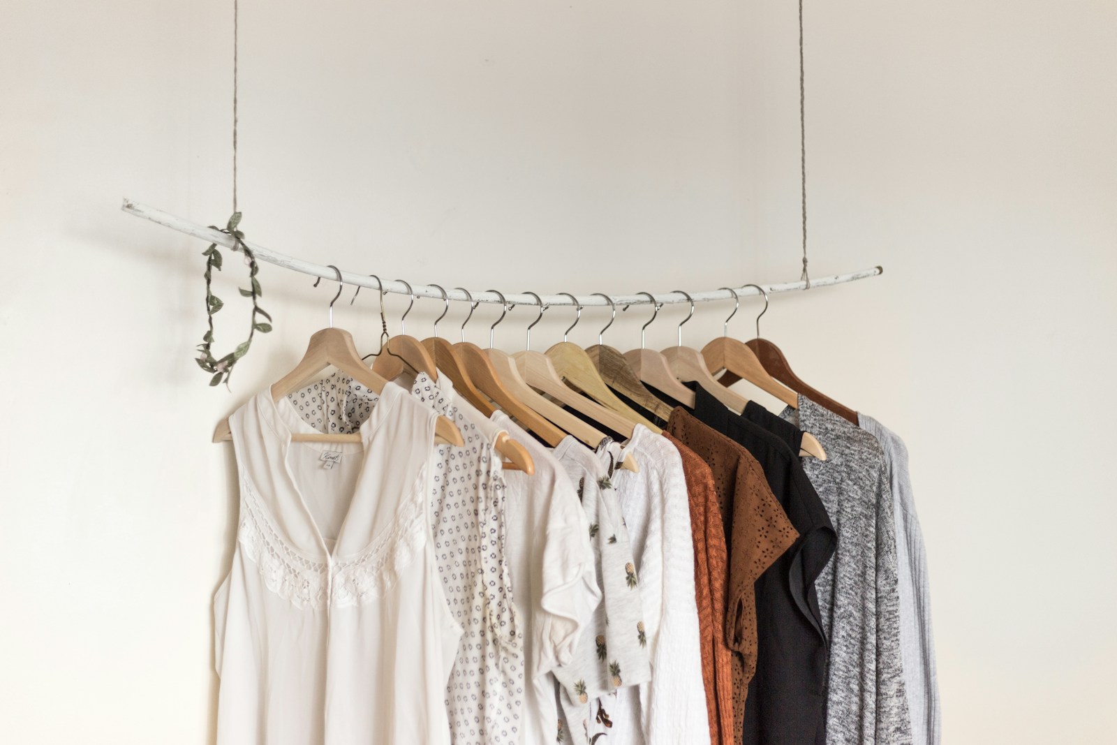 Clothes on wooden hangers hanging from a simple rope rail