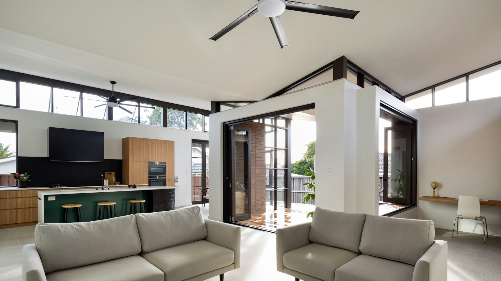 Bright living room with a large black ceiling fan above two grey sofas