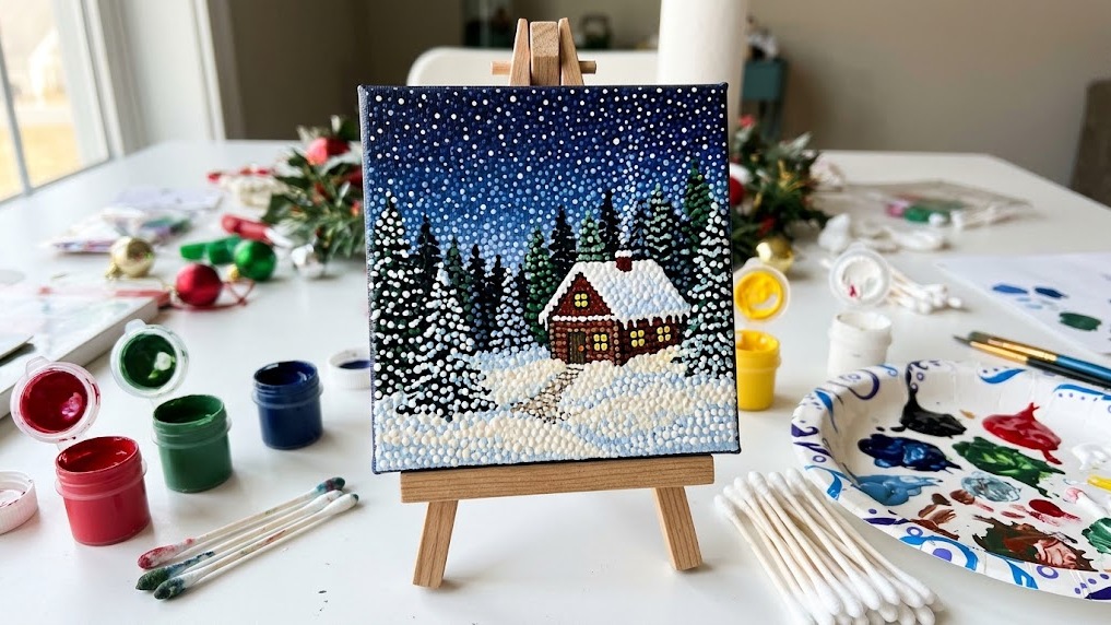 Cotton swab painting of a starry night sky over a snowy cabin