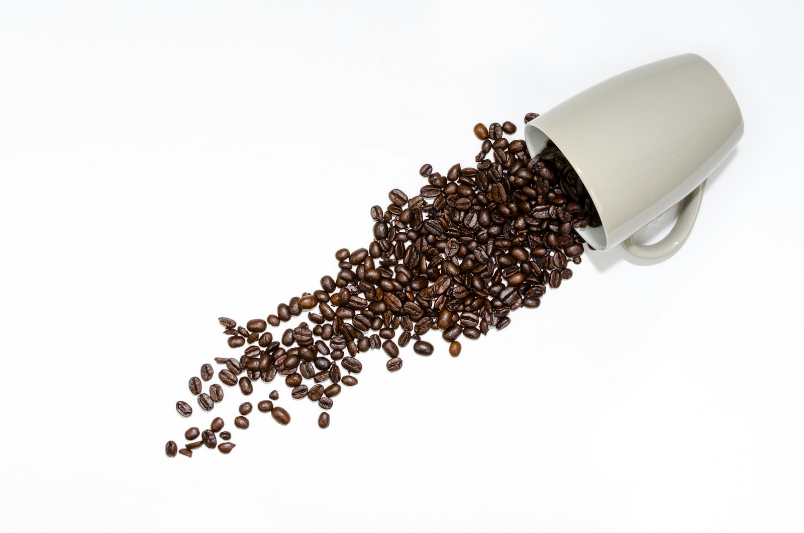 DIY gifts for dad: coffee beans spilling beside a gray ceramic mug