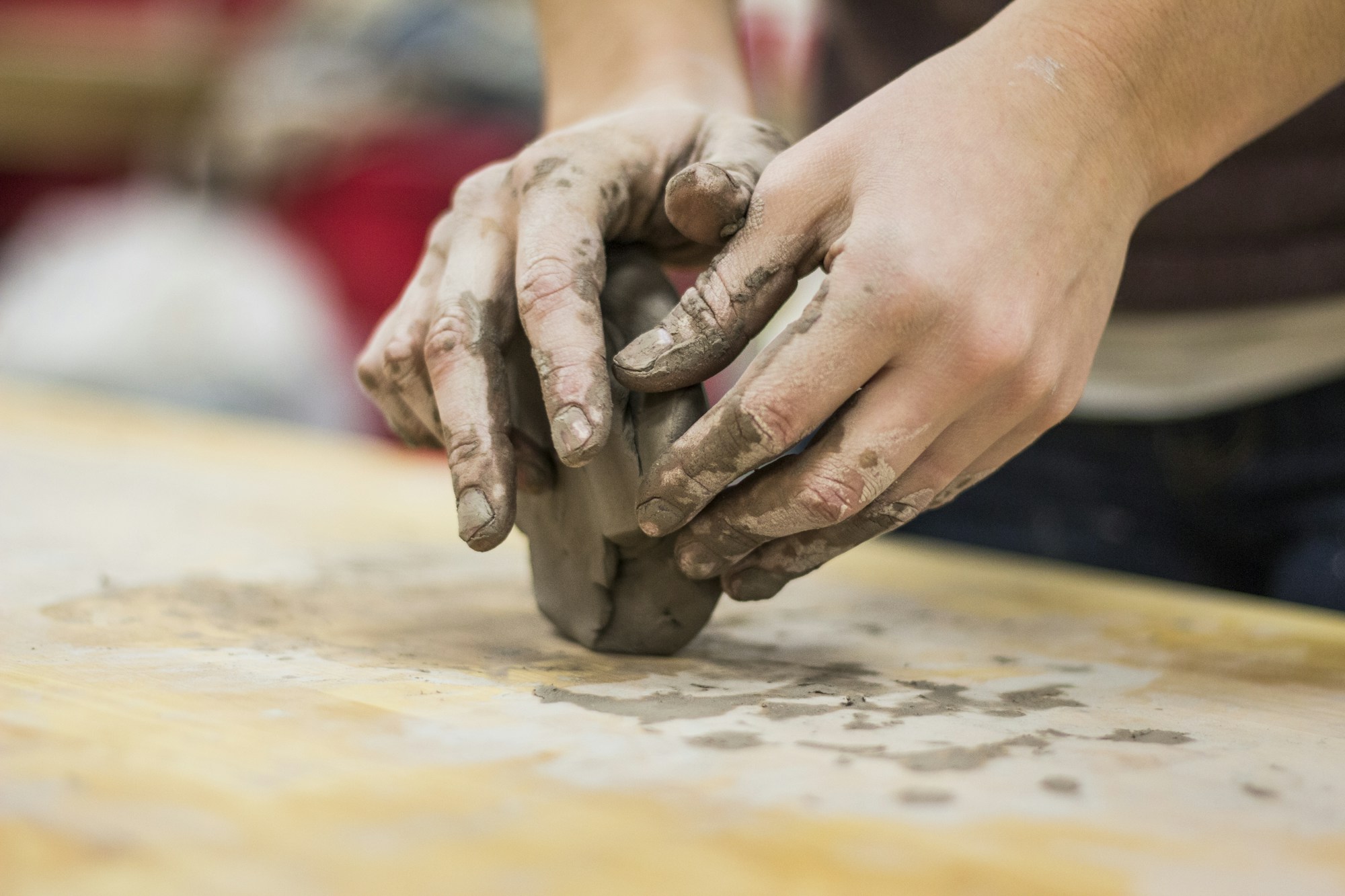 Clay covered hands shaping a lump of clay