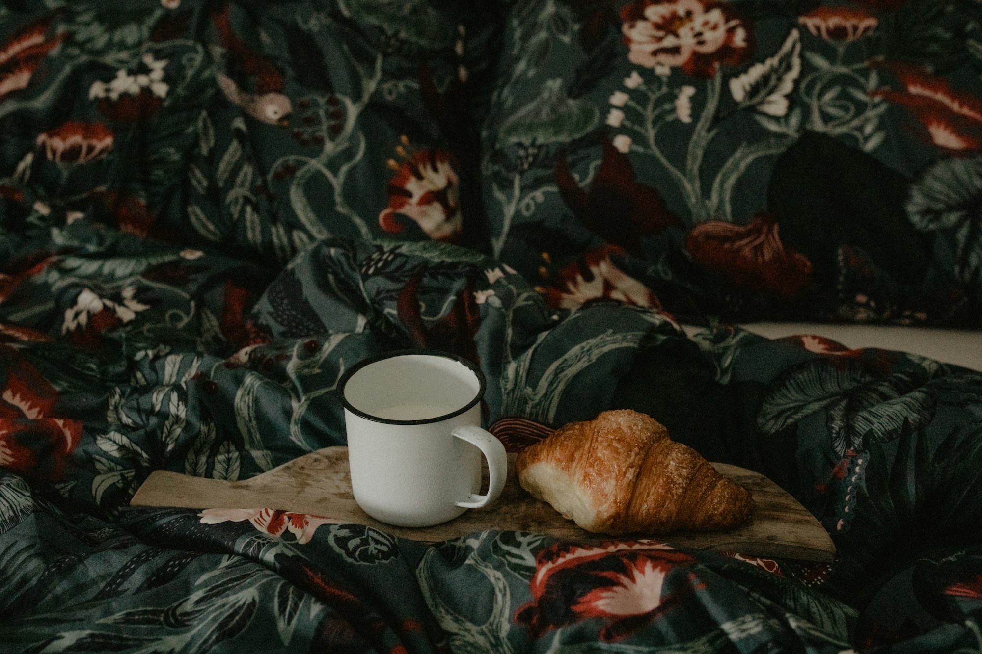 Cozy indoor picnic with a mug and pastry on a floral blanket