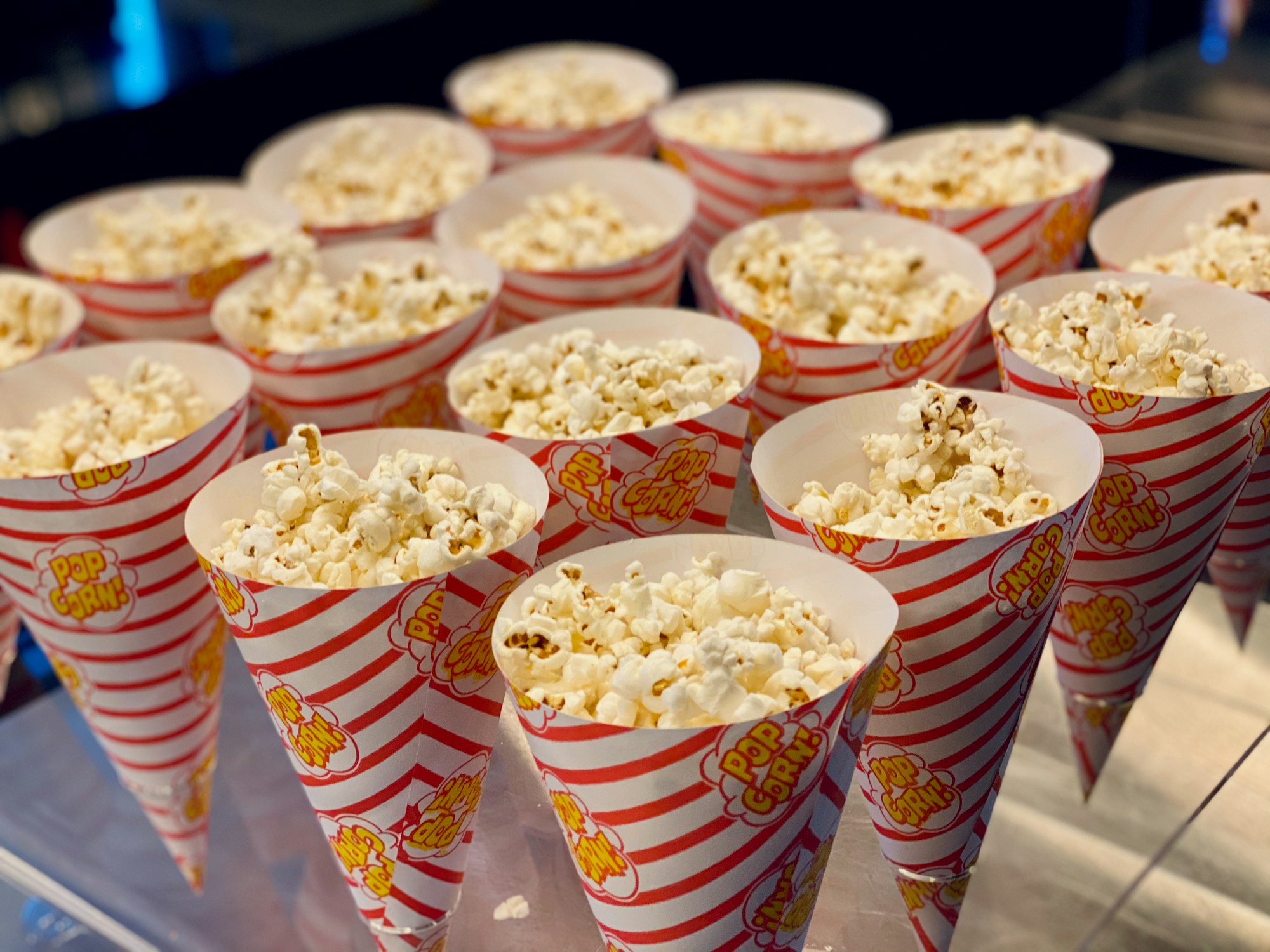 Rows of striped popcorn cups lined up for a date night at home popcorn bar