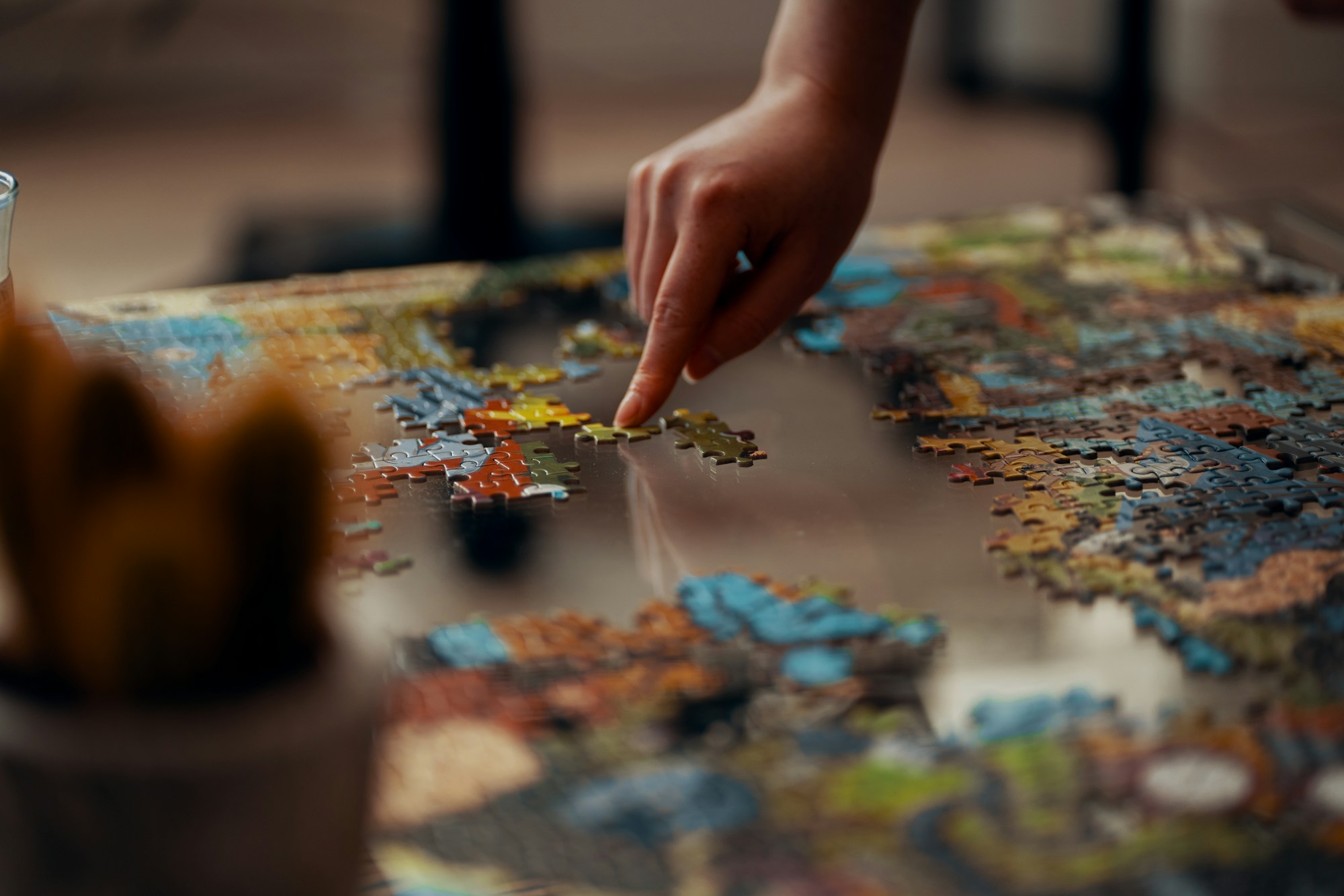 Hand placing a piece into a colorful jigsaw puzzle