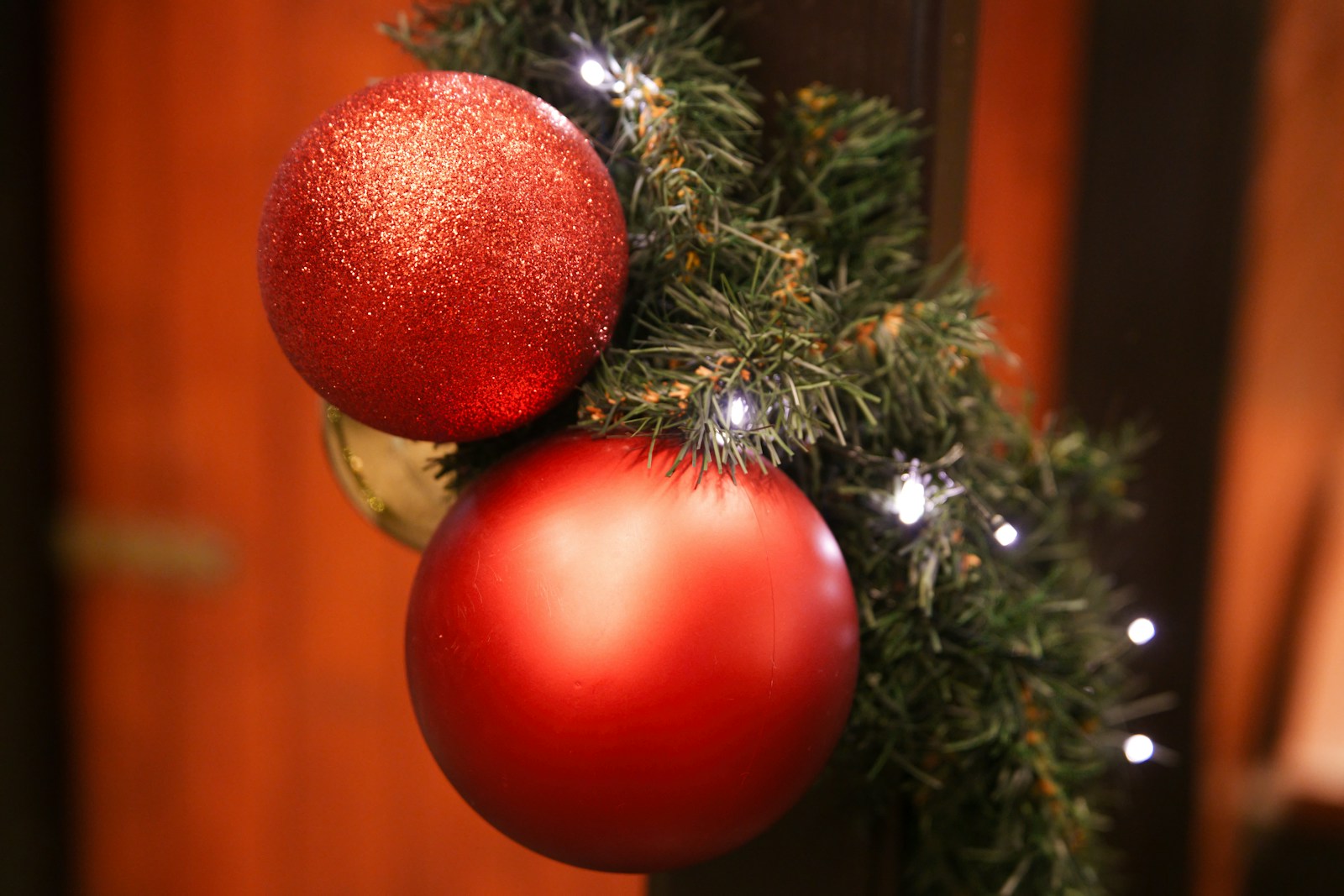 Red ornaments hanging from an evergreen garland