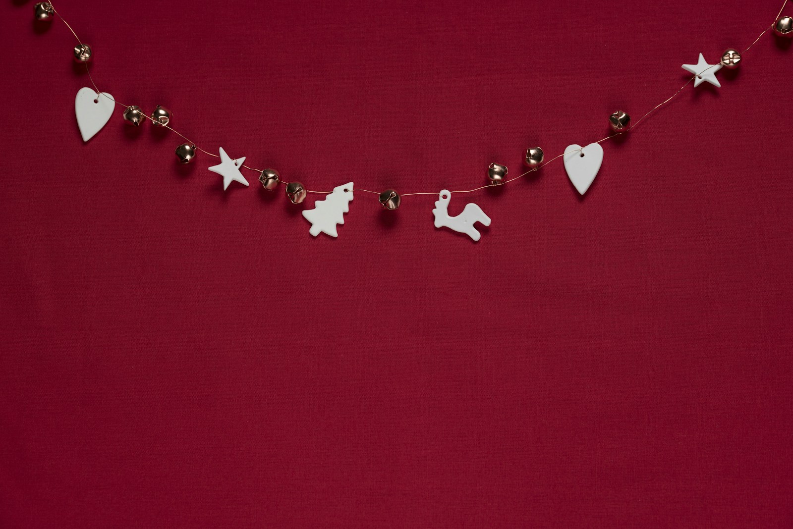 DIY Christmas garland of white wooden hearts, stars and trees on red twine