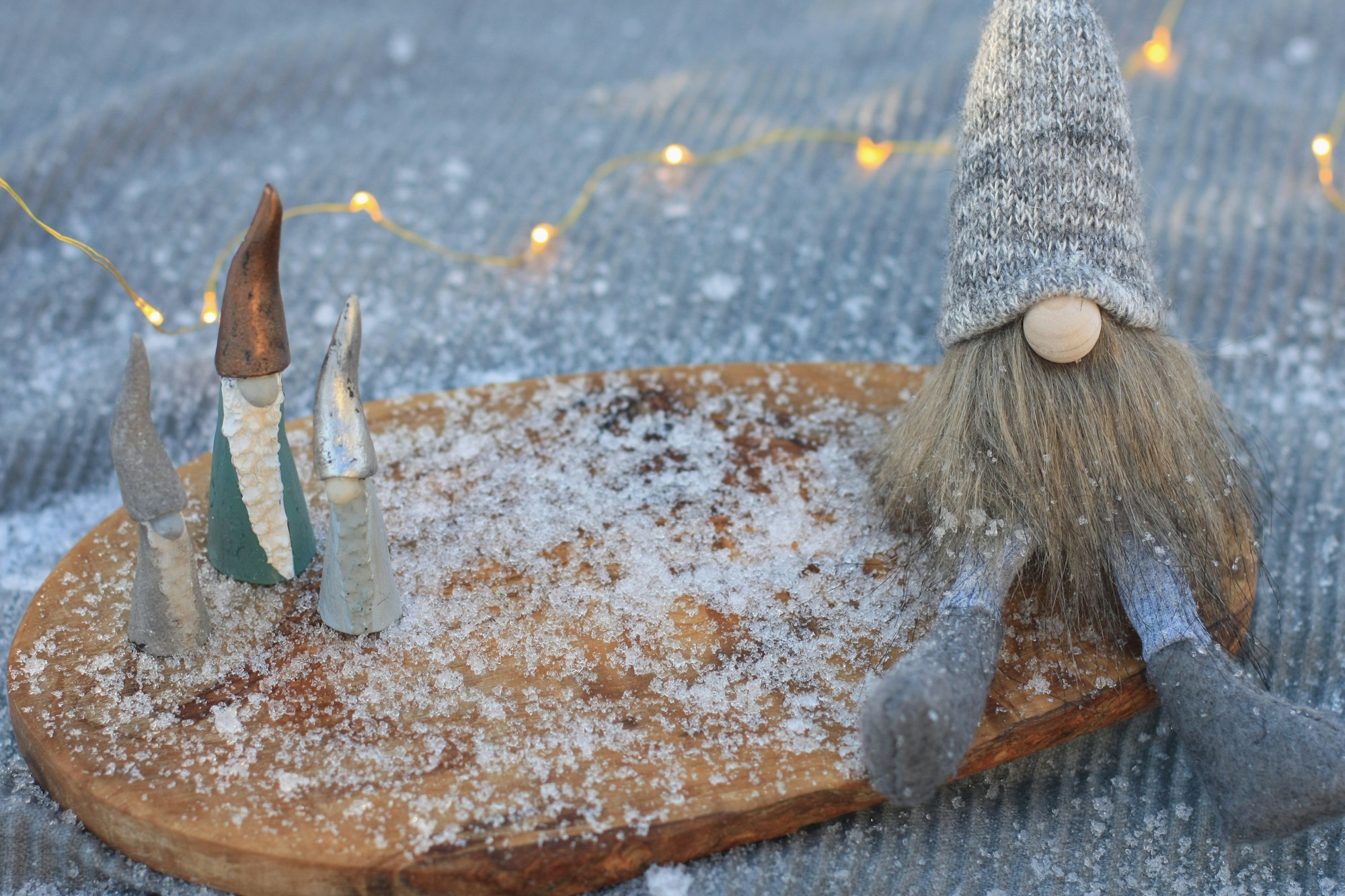 Small gnomes displayed on a round wood slice with faux snow