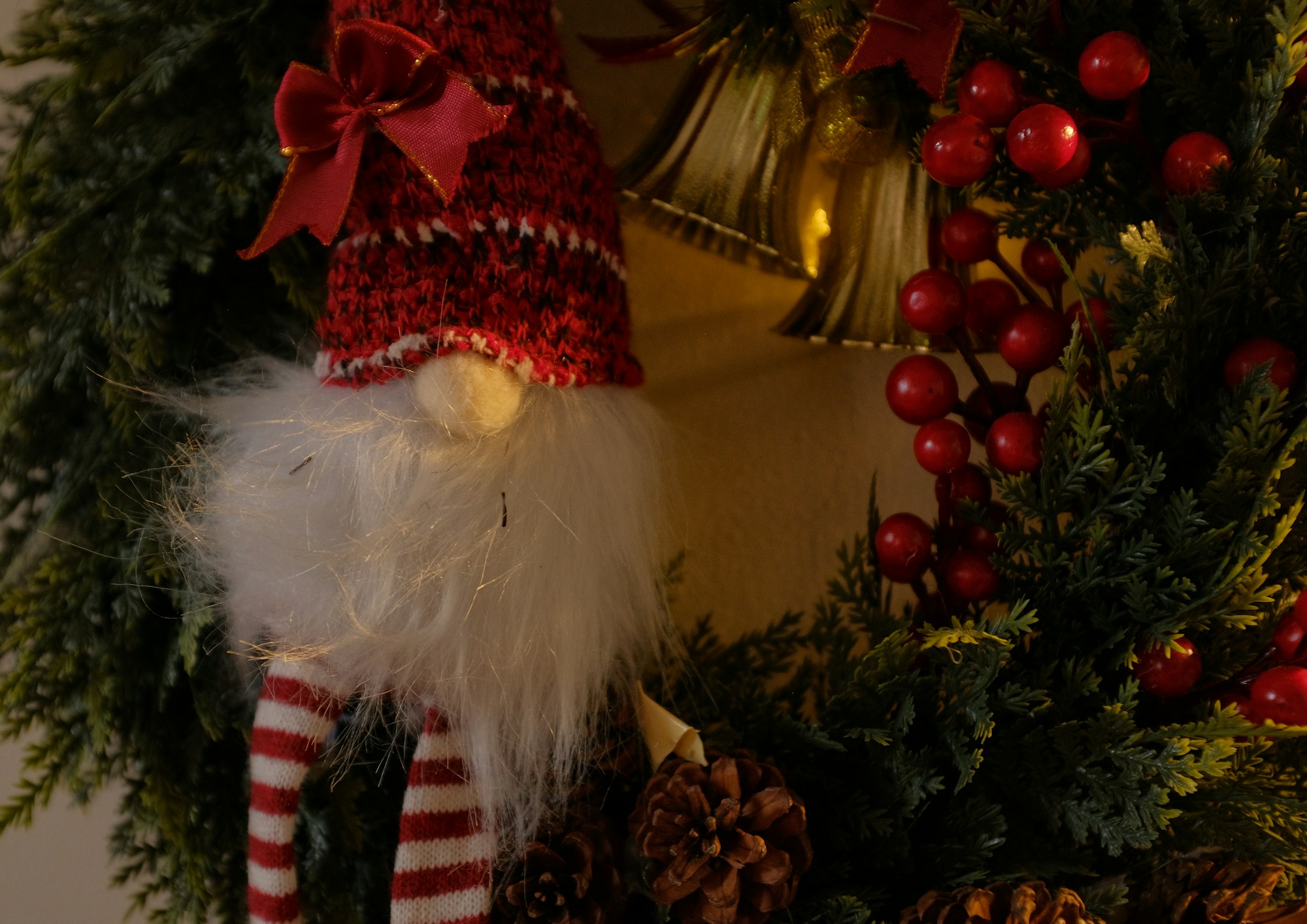Christmas gnome tucked into a pine wreath with berries and pinecones