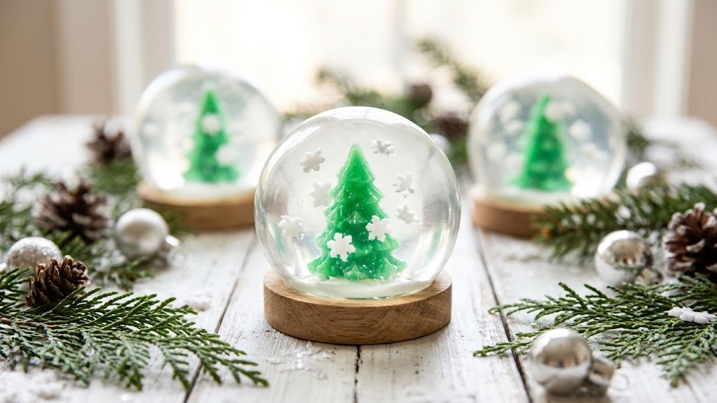 Clear DIY Christmas soap shaped like a snow globe with a tiny green tree and white snow inside