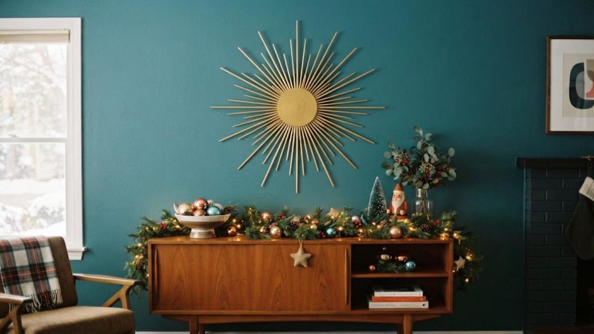 Handmade gold starburst made from skewers above a teak credenza with garland, midcentury Christmas decor