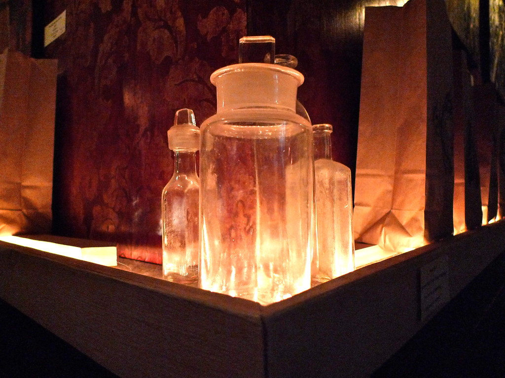 Glass apothecary jars with lids glowing in warm light on a wooden display