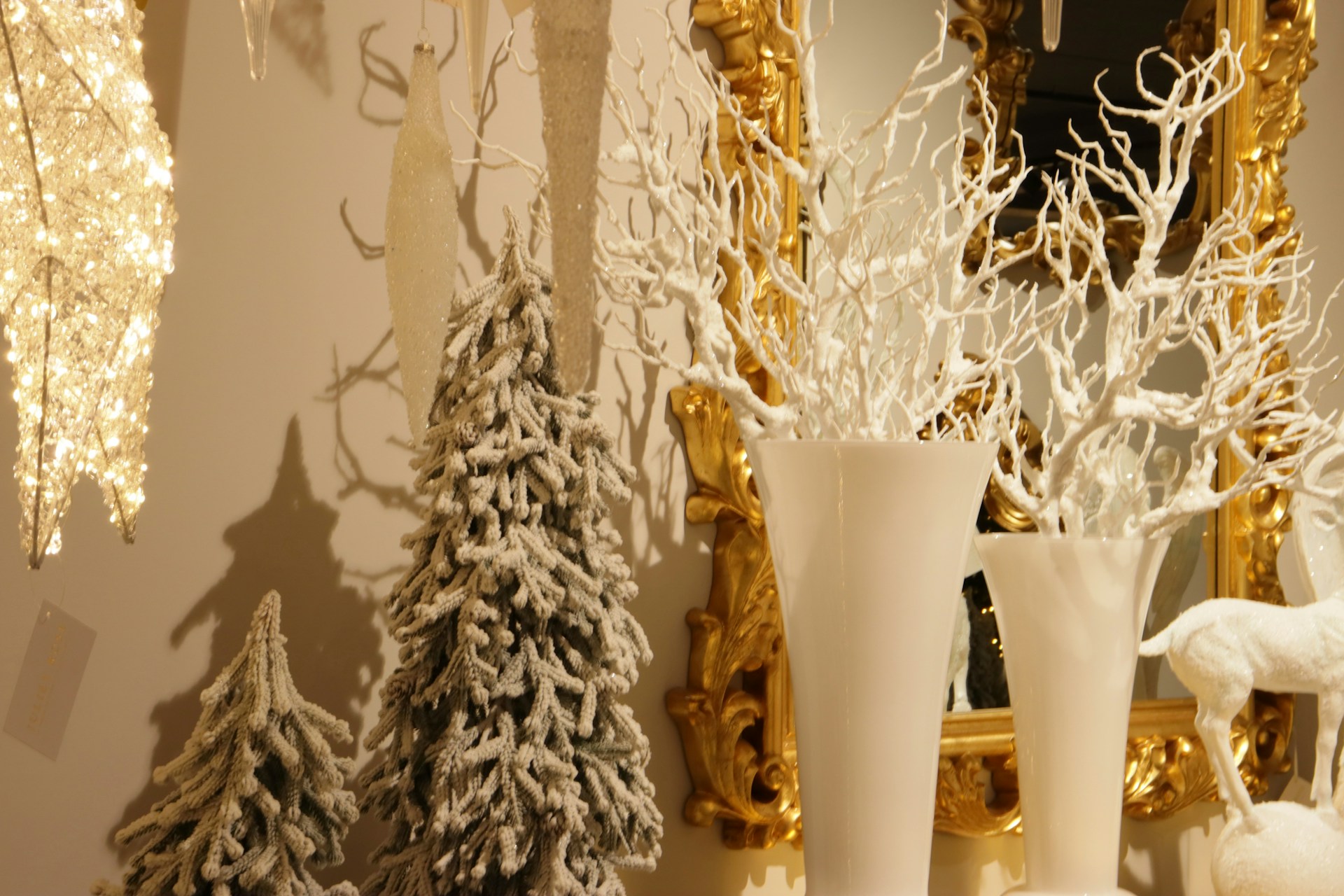 White branches and flocked mini trees displayed in tall white vases