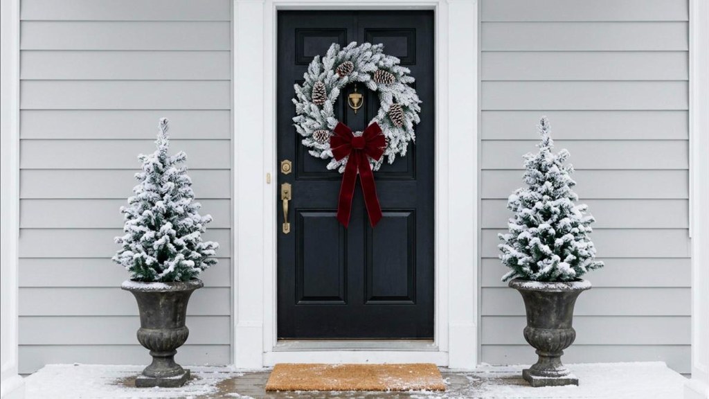 Snowy flocked wreath with a red velvet bow on a front door