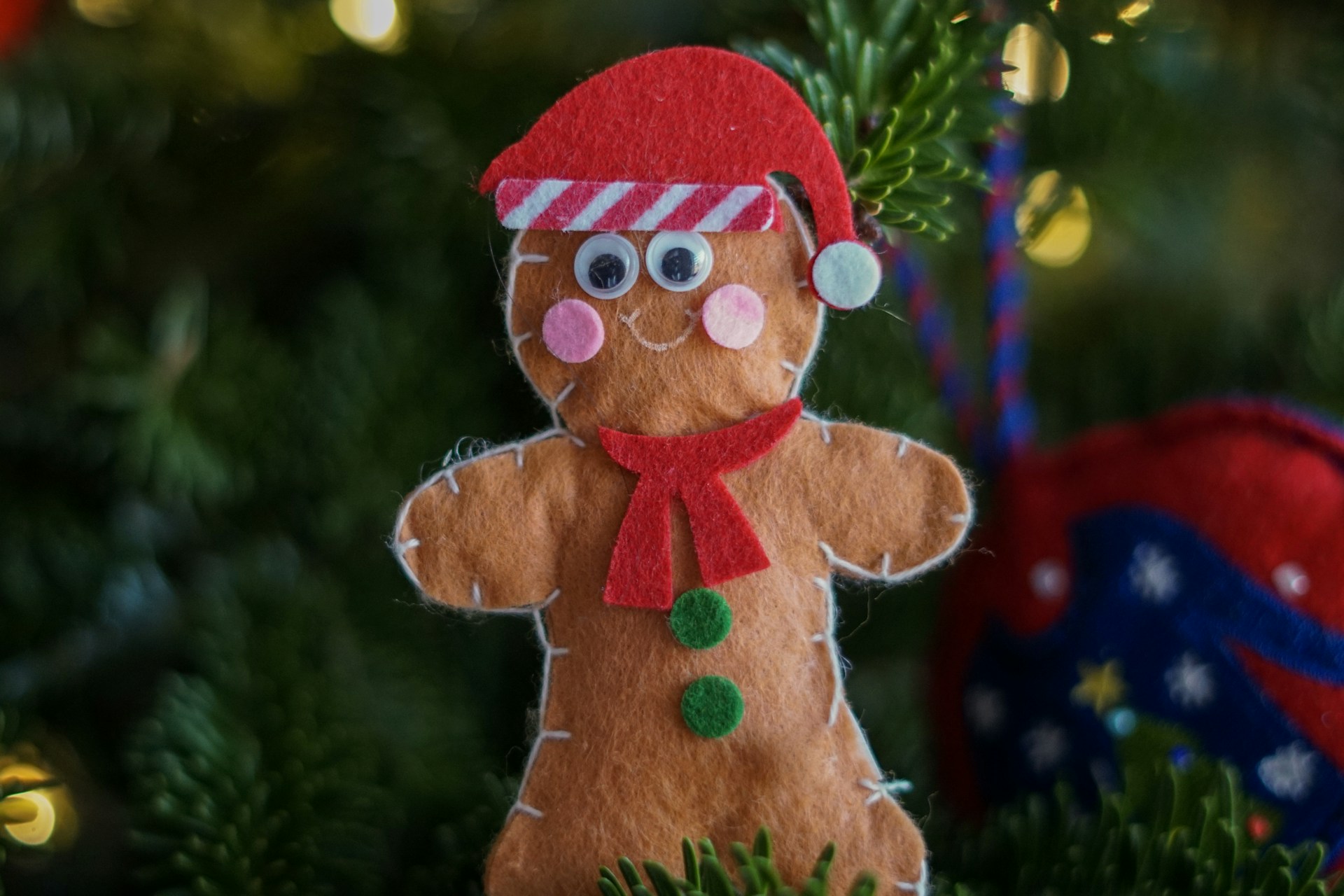 Felt gingerbread man ornament with a red scarf on a Christmas tree