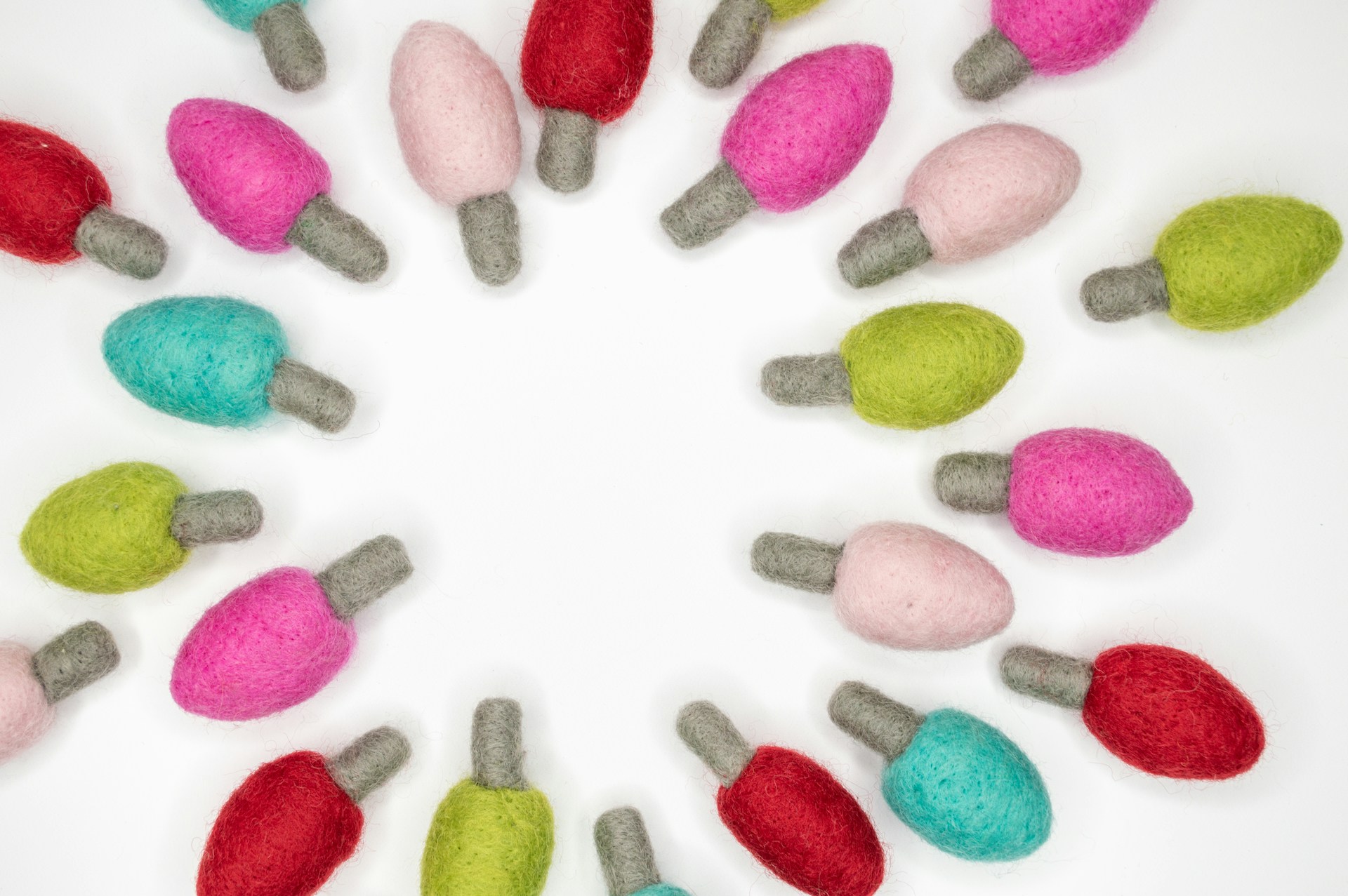 Colorful felt light bulb shapes in pink, teal, lime and red on a white background