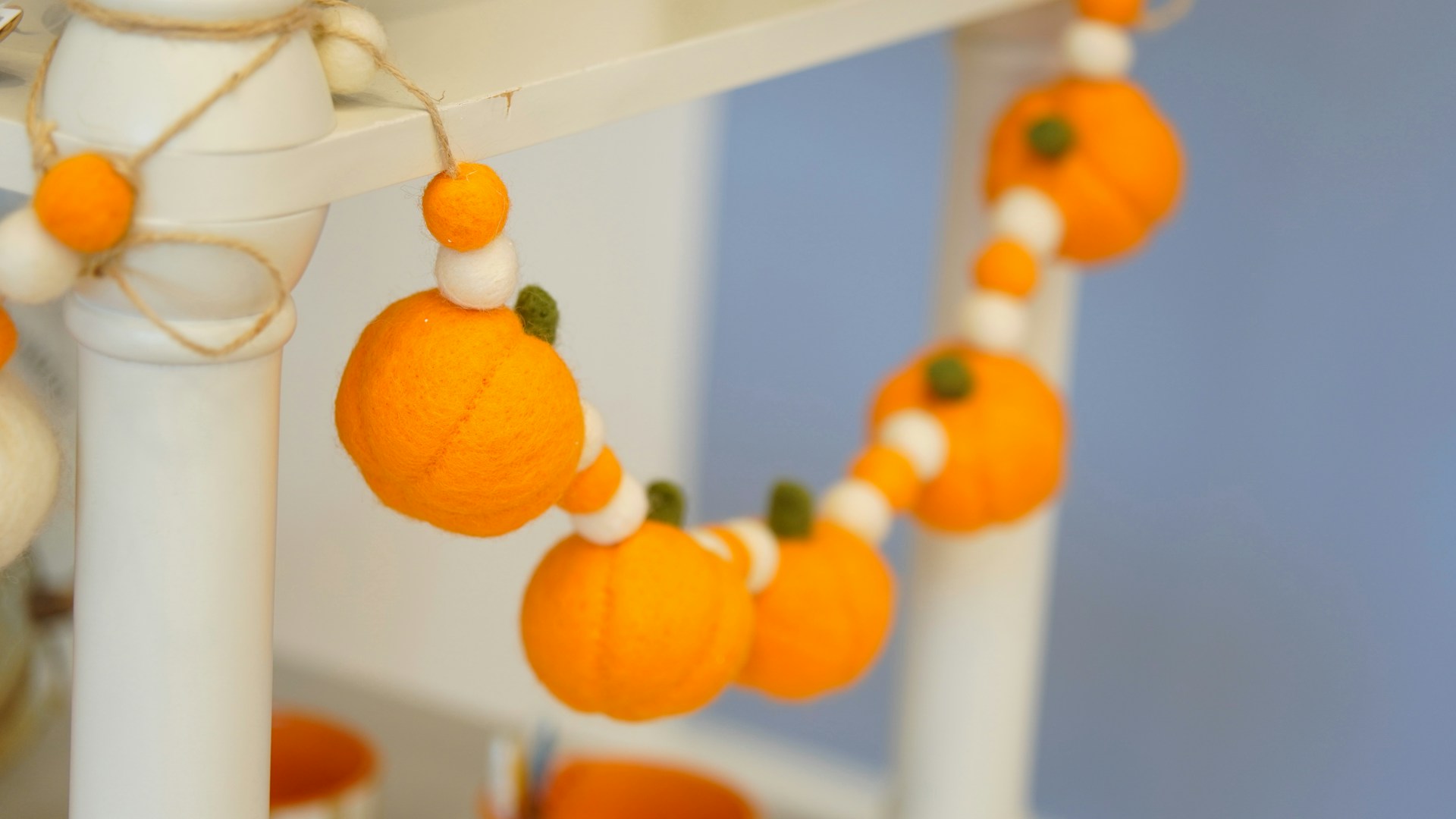 Orange felt pumpkin garland with white beads draped along a white railing