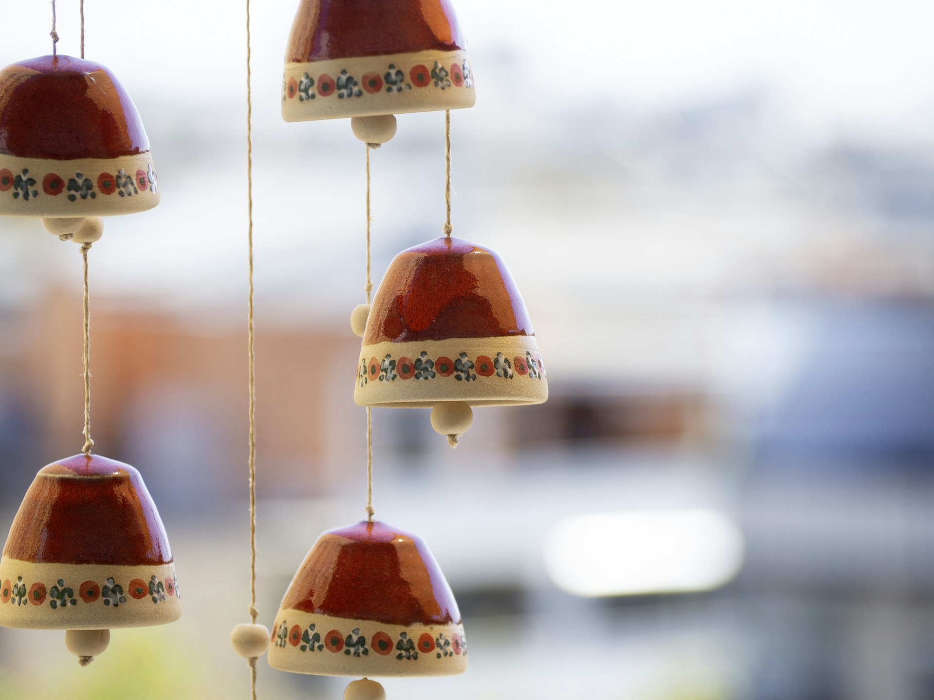 Red ceramic bells with tiny folk flowers hanging by a window
