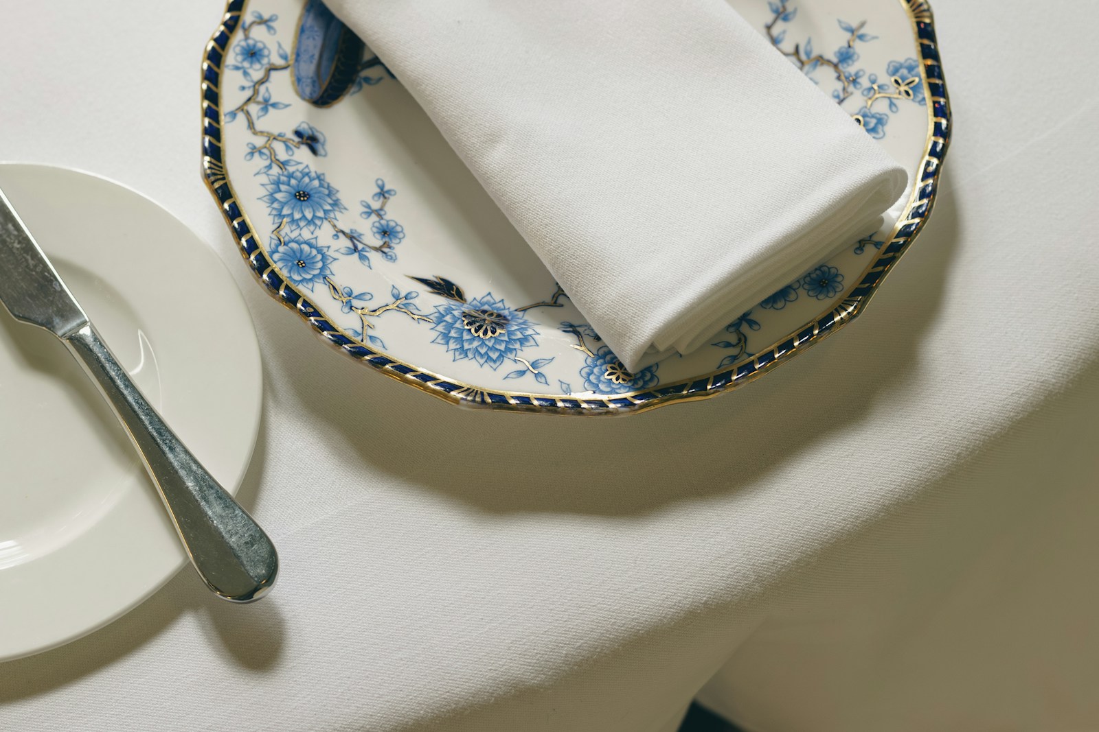 Formal place setting with a floral plate and folded white napkin