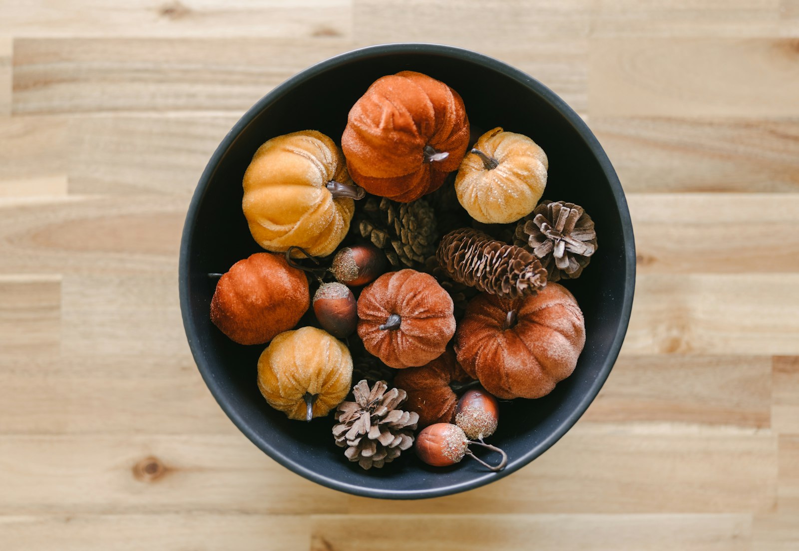 Faux pumpkin makeovers styled in a dark bowl with mini pumpkins, gourds and pinecones