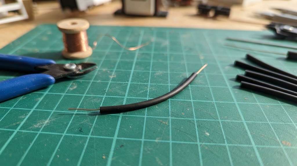 Copper wire threaded through thin black rubber tubing to make a tiny hose