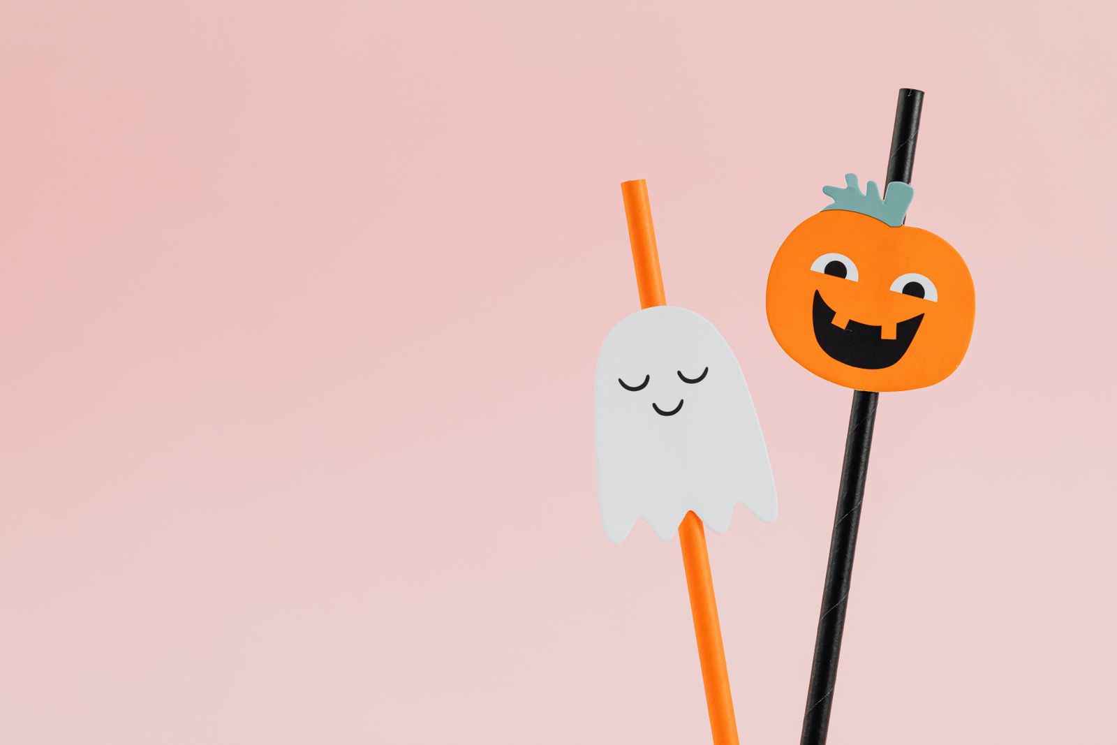Paper ghost and pumpkin toppers on striped drinking straws
