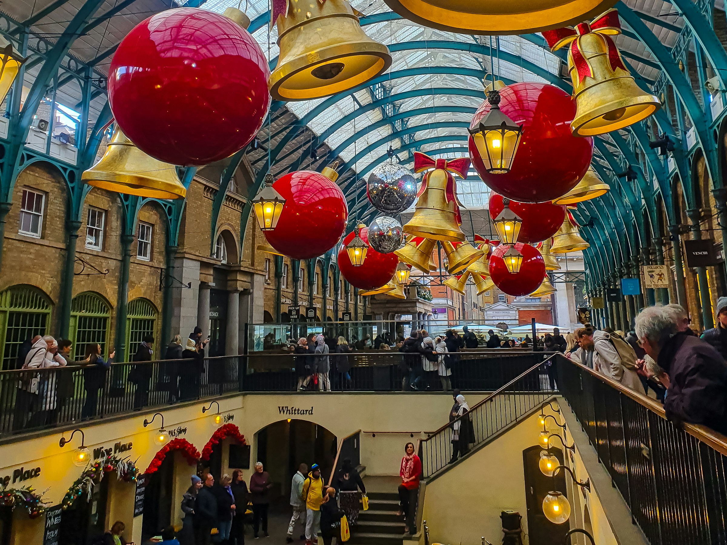 Huge red baubles and gold bells hanging from the glass roof of a covered market