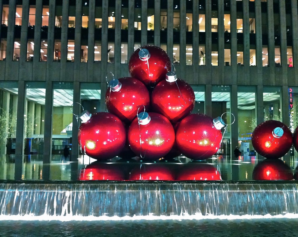 Giant Christmas ornaments stacked in a red pyramid beside a fountain in New York City