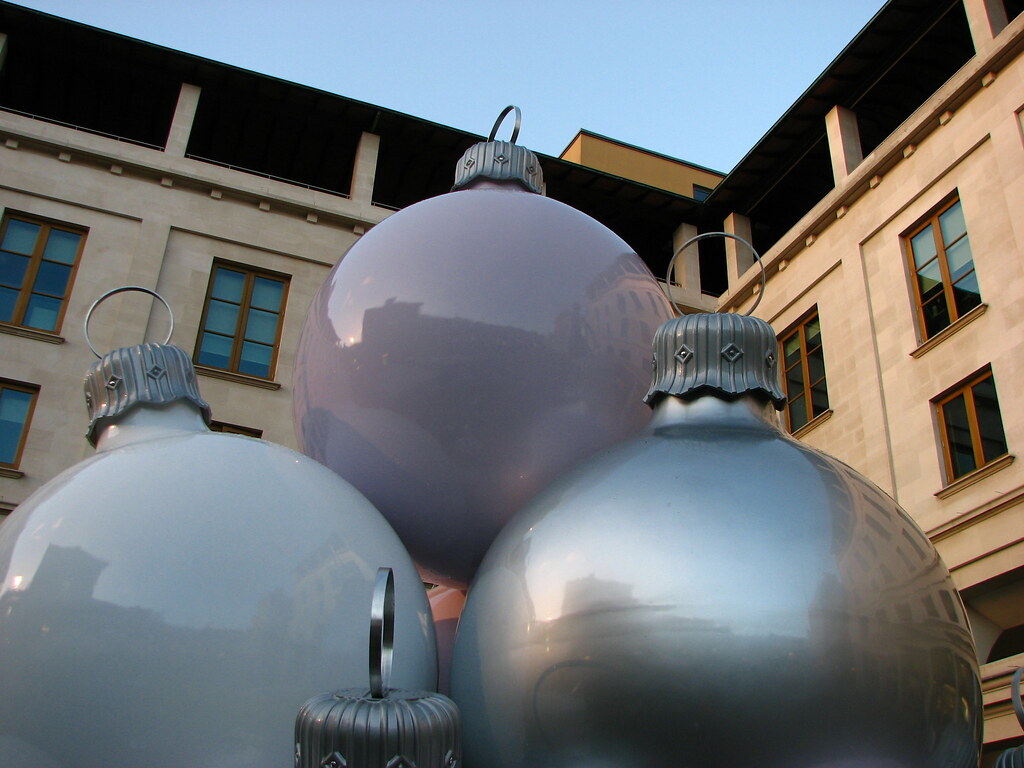 Three oversized silver and white baubles grouped together in a city courtyard