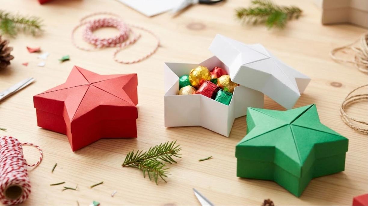 Red, white and green folded paper star gift boxes, one open with foil wrapped chocolates
