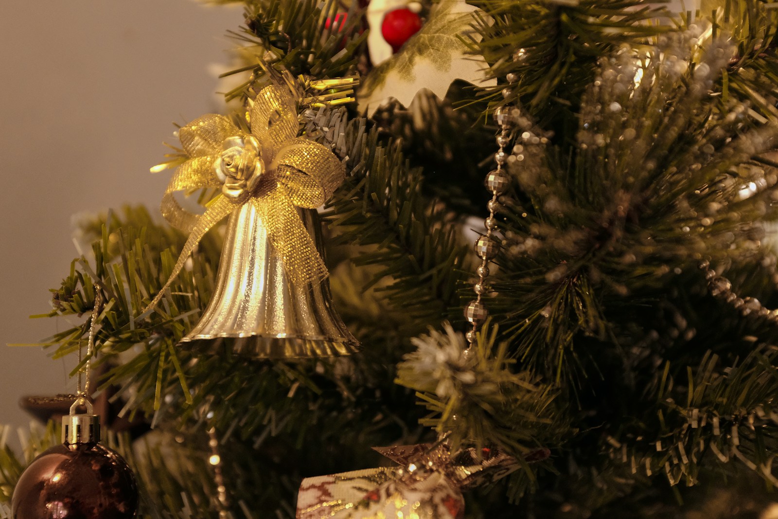 Gold bell and garland on a decorated Christmas tree