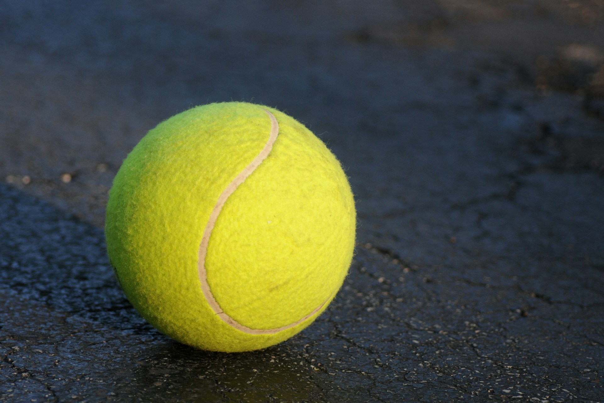 Yellow tennis ball on a dark floor