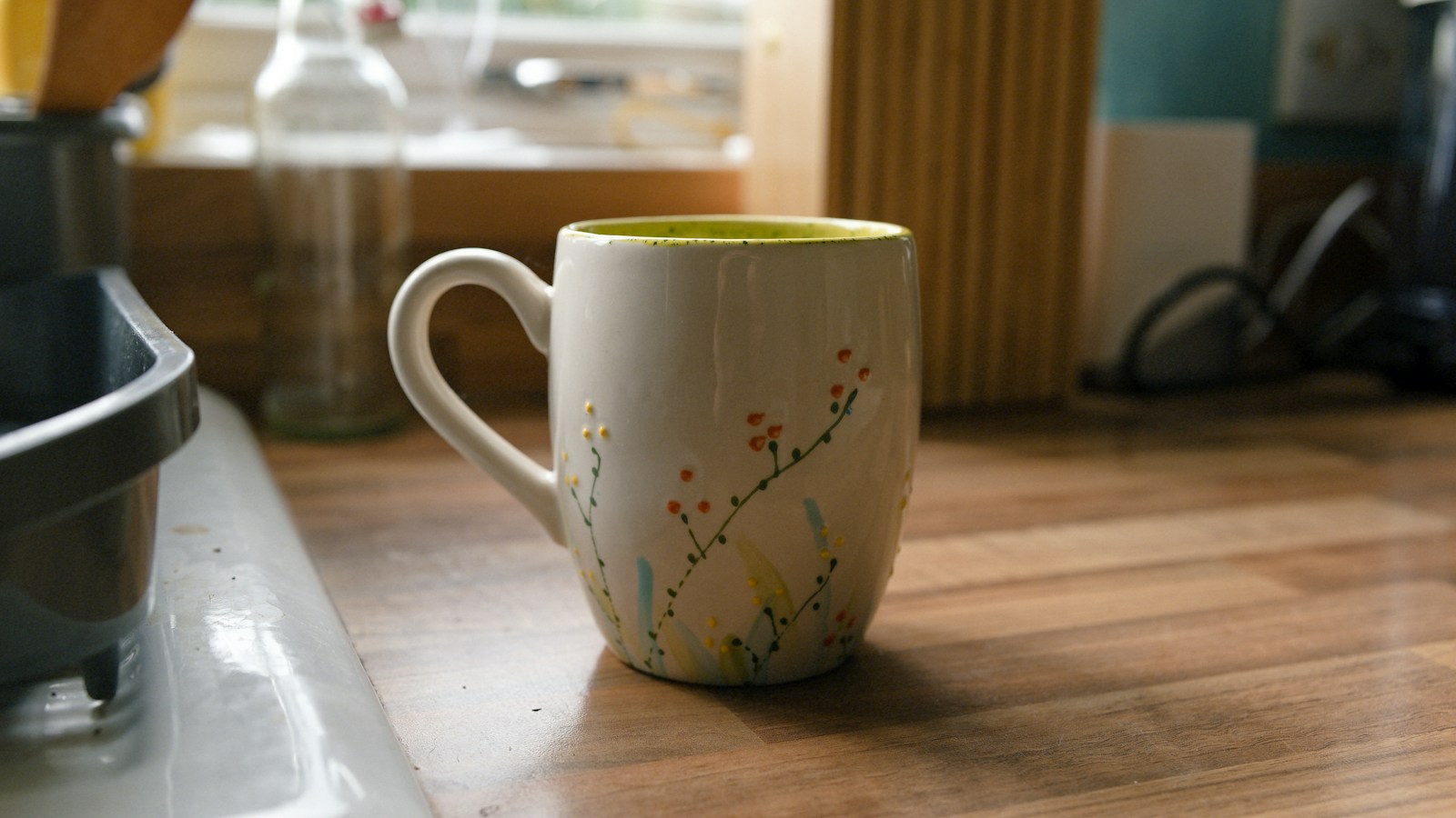 White mug hand painted with tiny wildflowers on a wooden counter