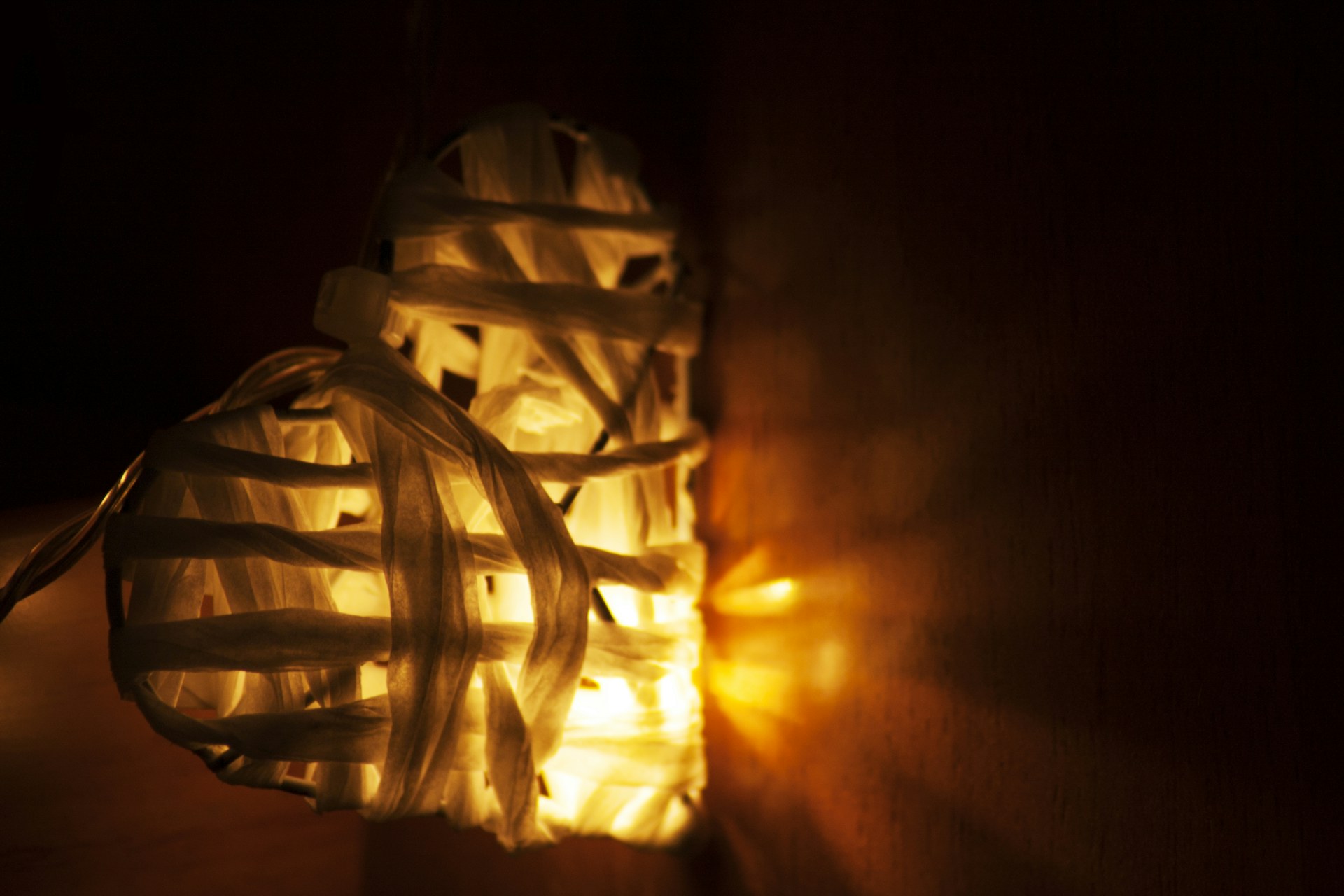 Woven white heart ornament glowing with a warm battery light in a dark room