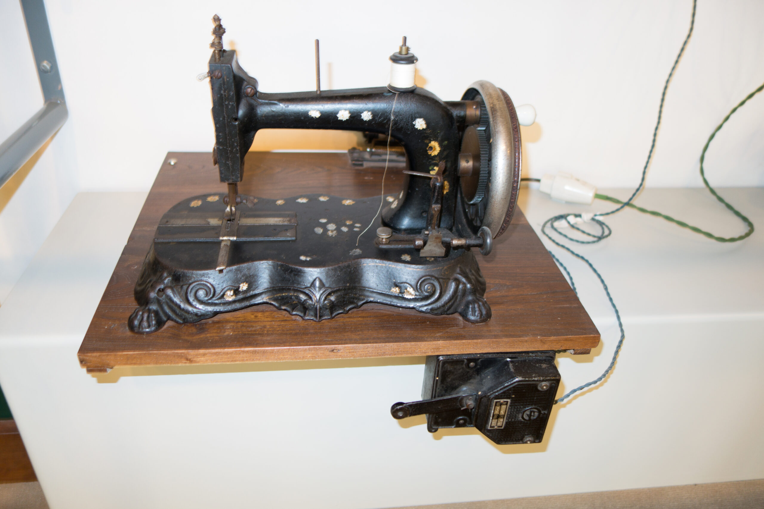 Ornate antique sewing machine with gold detail on a wooden base