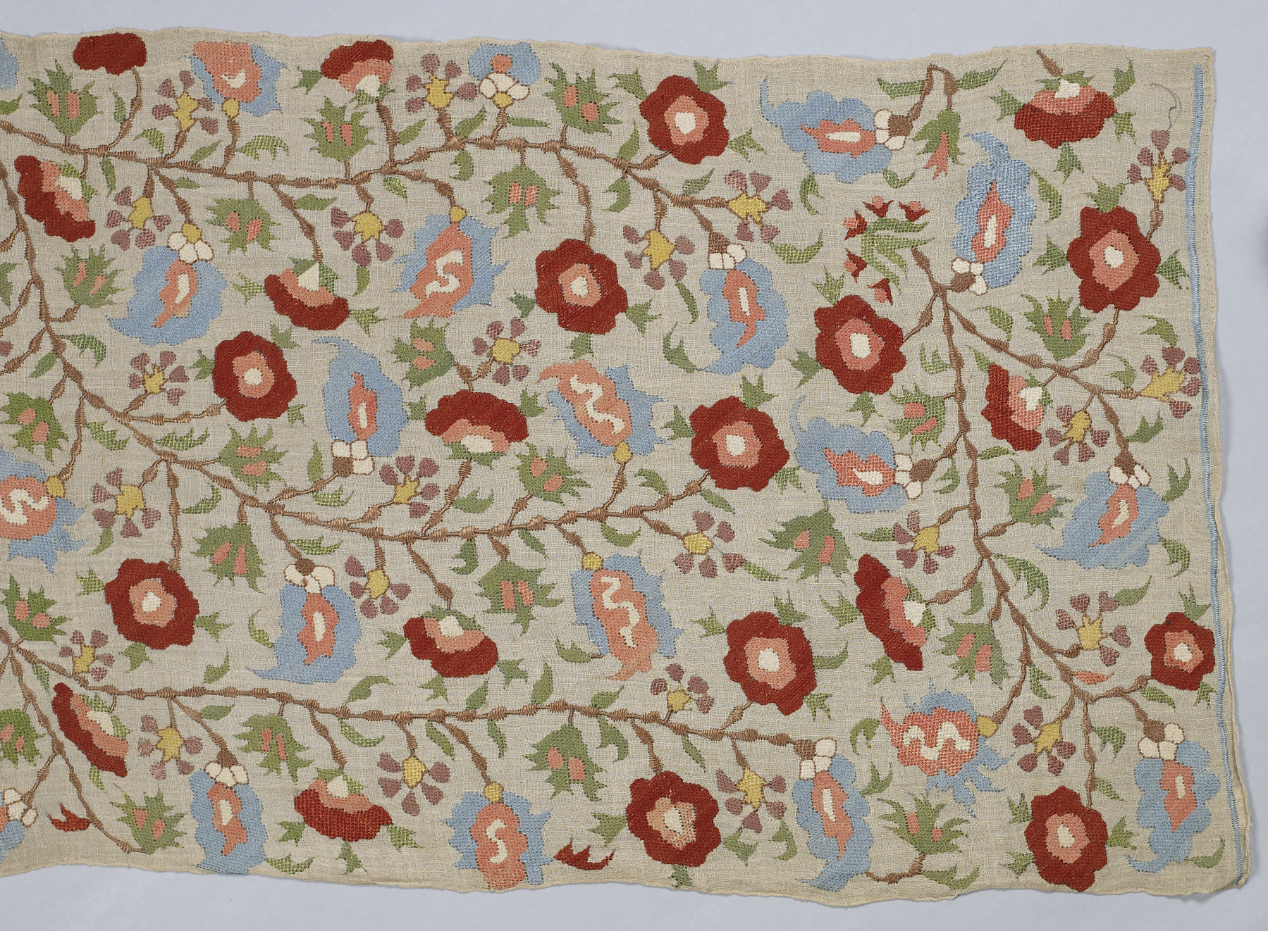 Old hand embroidery with red and blue flowers, a detail of a museum textile