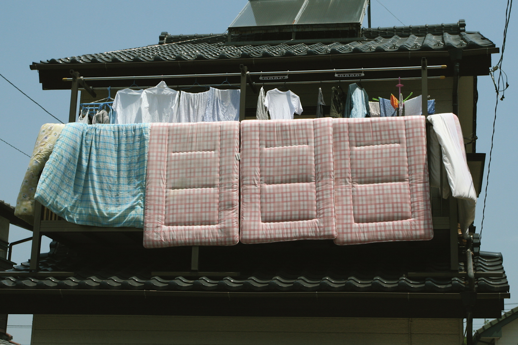 Futons hanging over a balcony railing to air out in the sun