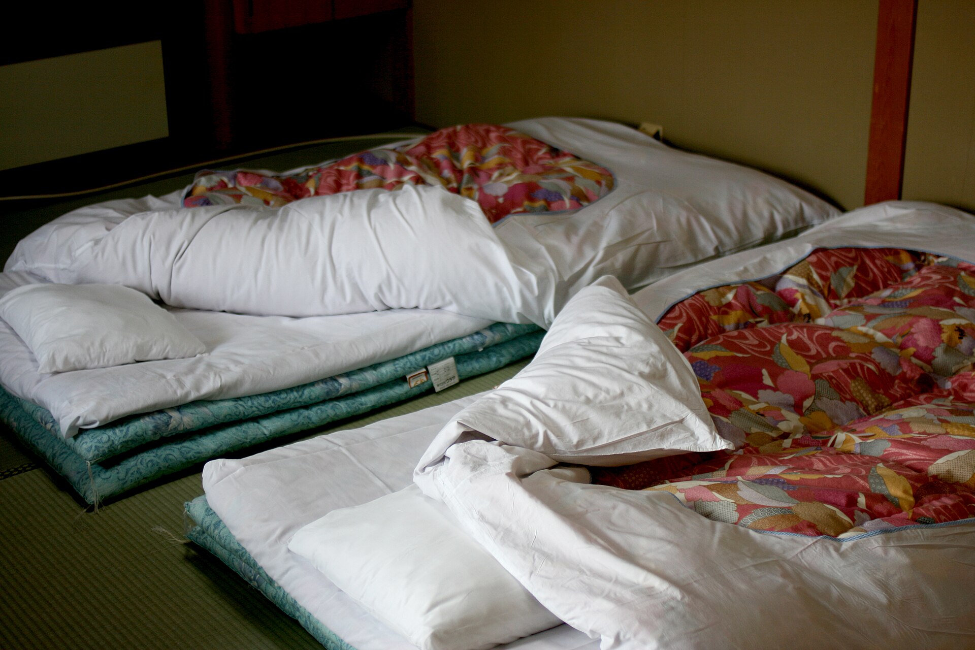 Thick futon mattresses and quilts laid in layers on a tatami floor