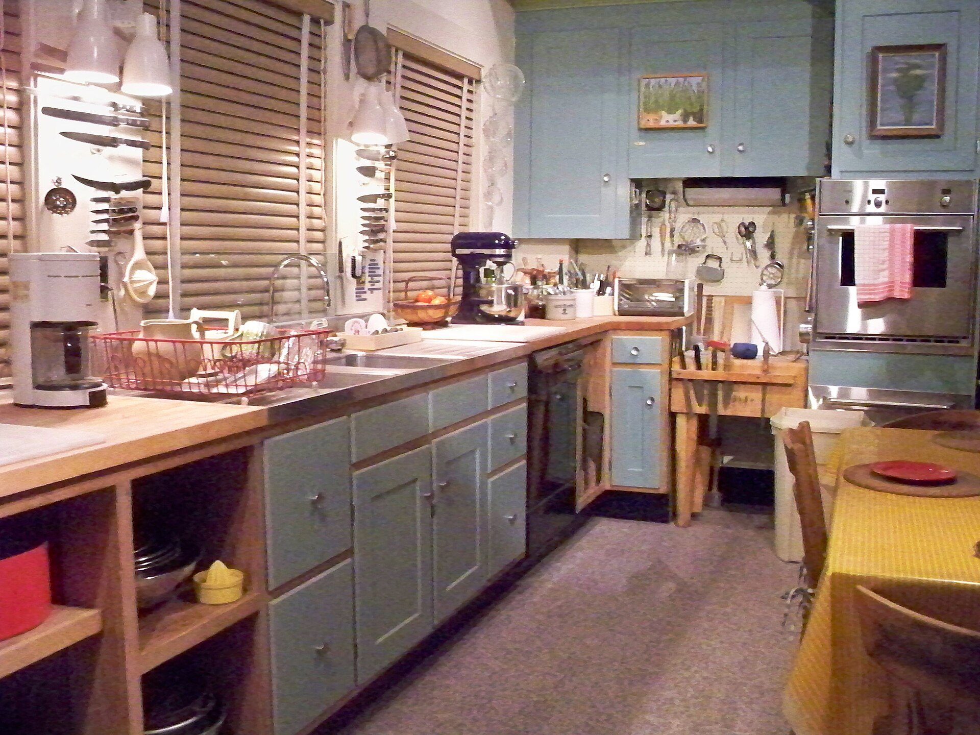 Blue green cabinets, open shelves and long counters in the kitchen exhibit at the Smithsonian