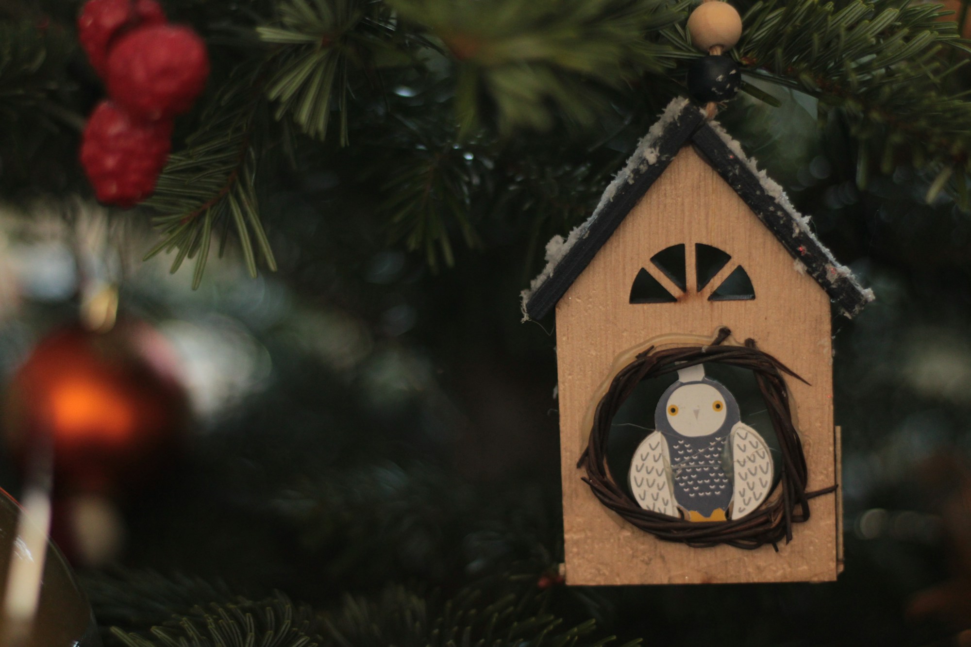 Thomas Kinkade Christmas style wooden bird house ornament on a tree