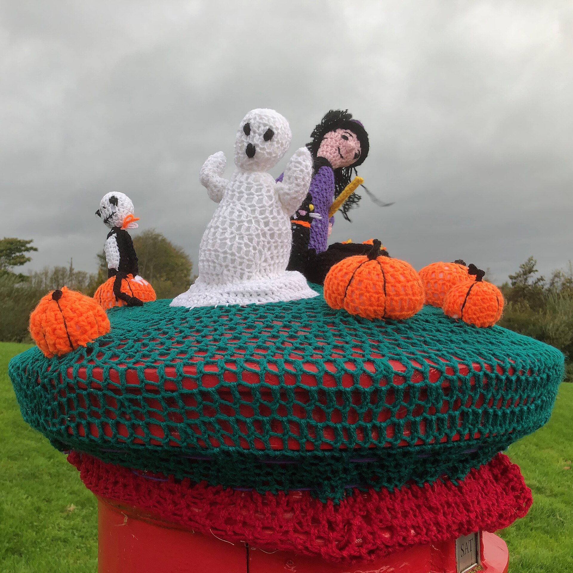 Crochet orange pumpkins with knitted ghost and witch figures on a yarn topper