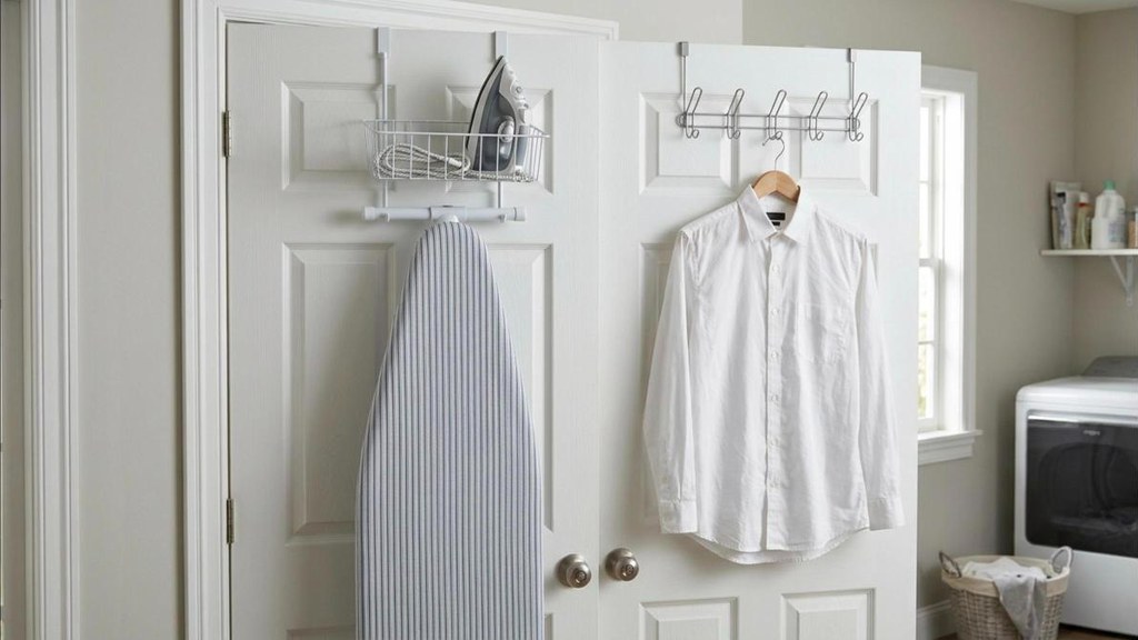 Over the door ironing board holder with hooks on a white laundry room door