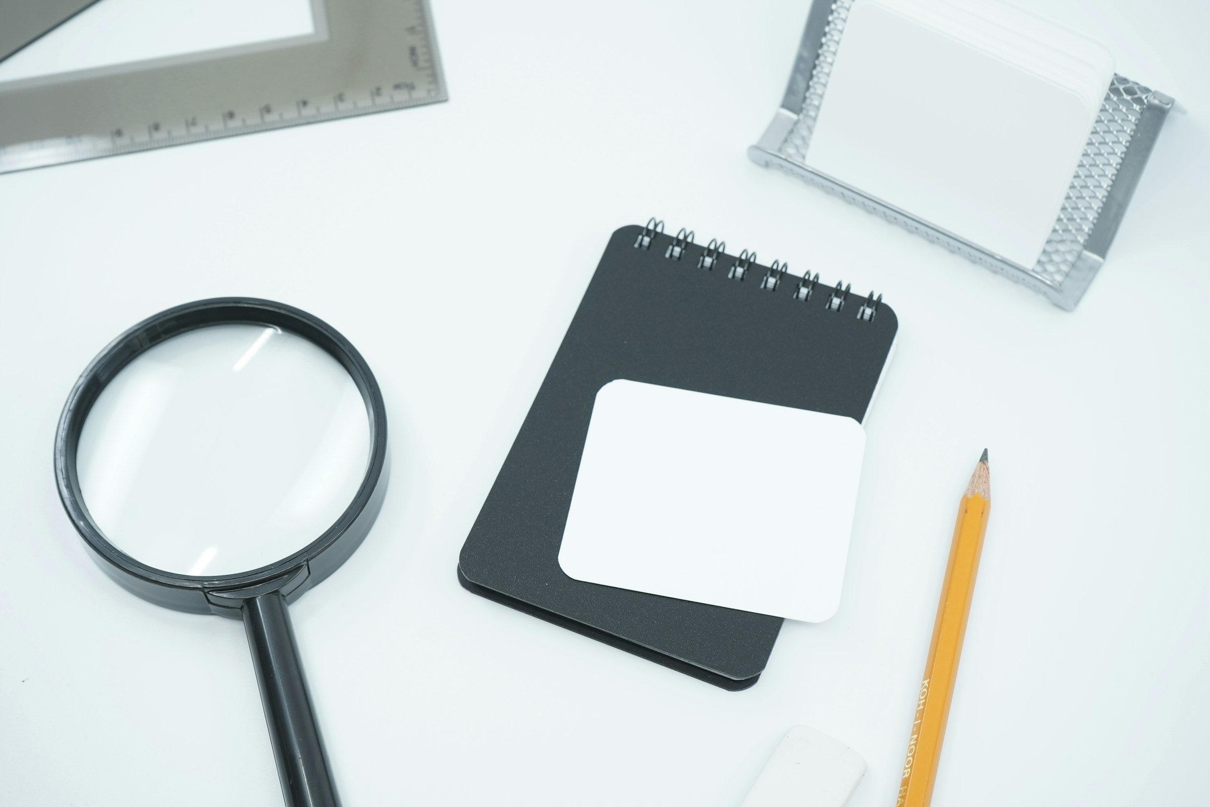 Magnifying glass resting on white paper beside a notebook