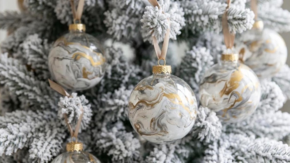 Clear ornaments swirled with white, gray and gold paint to look like marble on a flocked tree