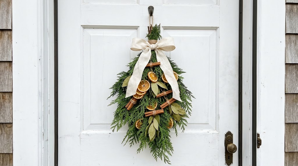 Door swag of dried orange slices, bay leaves, cinnamon sticks and cedar tied with twine and linen ribbon