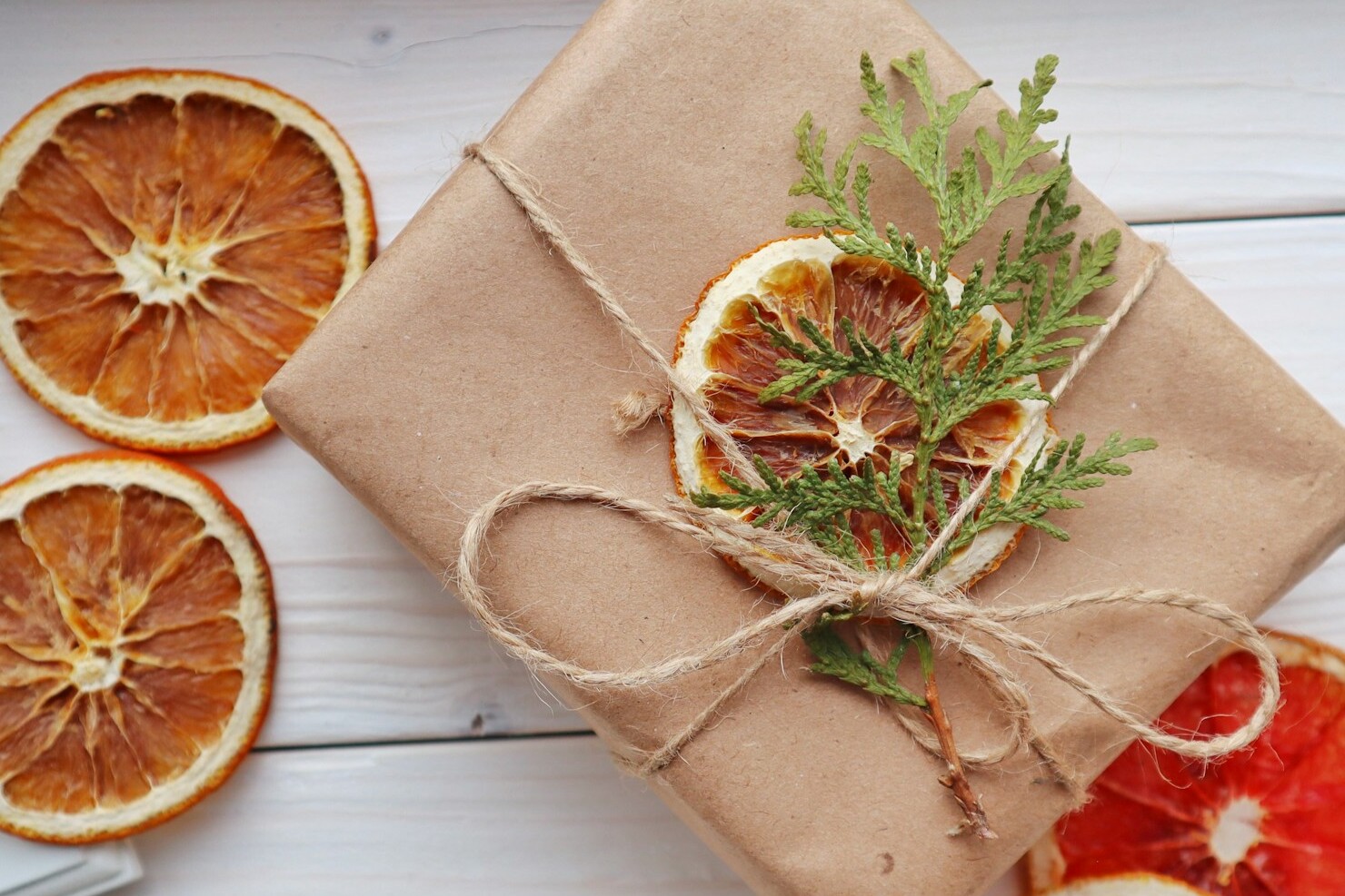 Kraft paper gift tied with twine, a dried orange slice and a cedar sprig