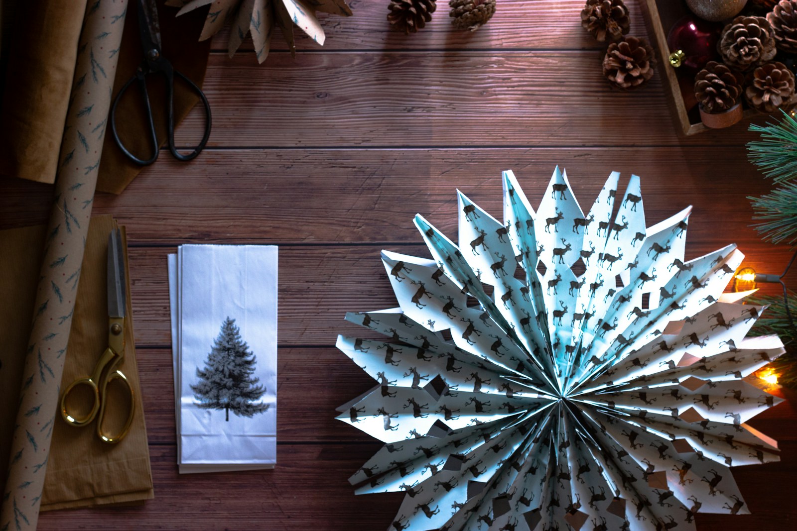 Creative money gifts: folded paper fan rosettes with wrapping supplies on a wooden table