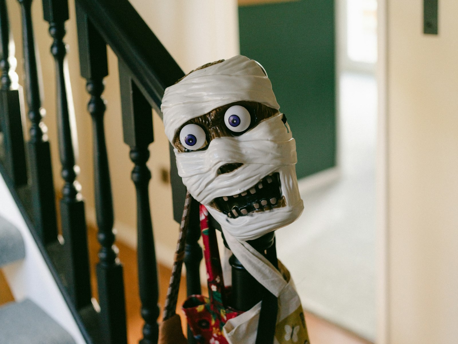 Mummy decoration with googly eyes wrapped on a stair railing post