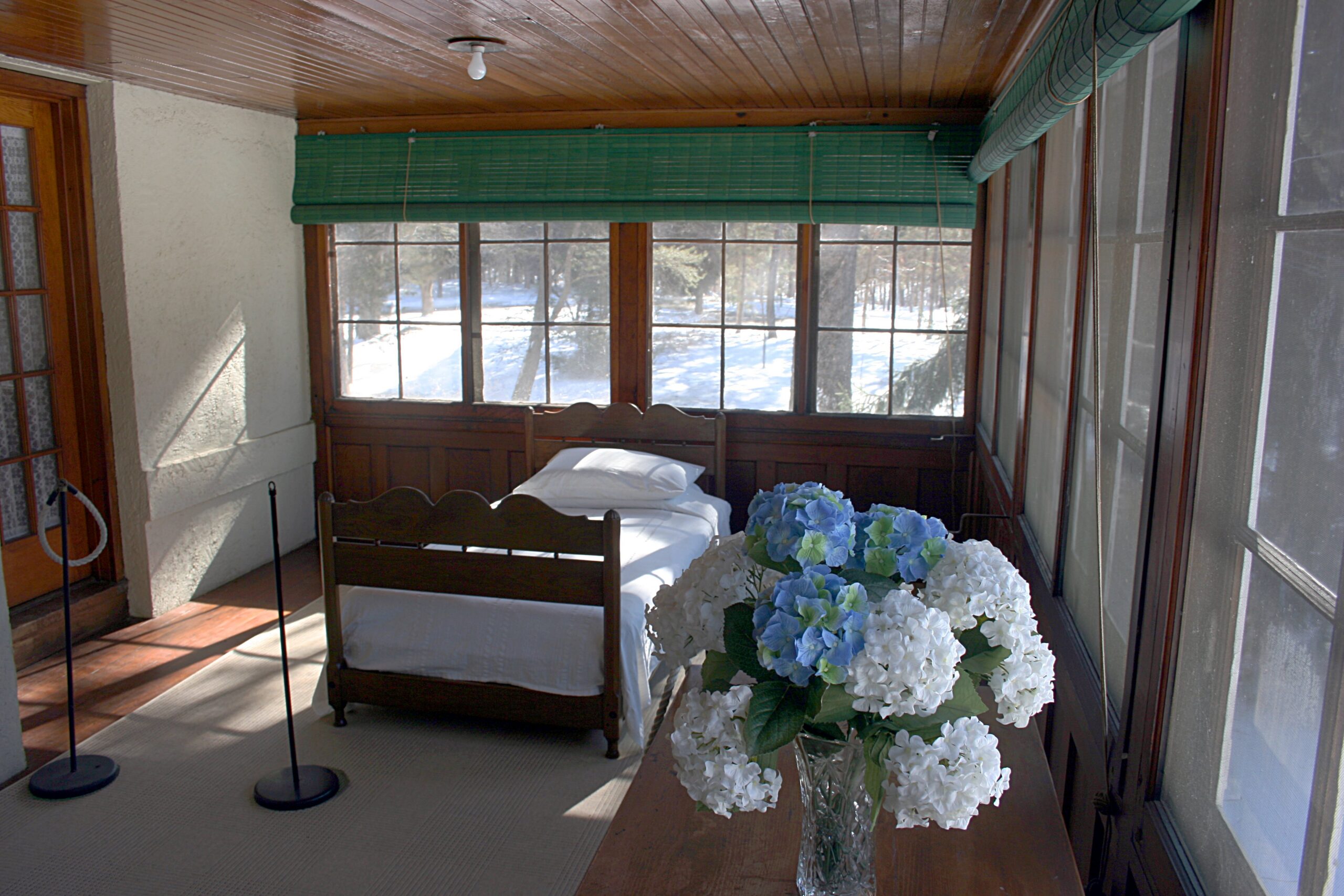 Old house features sleeping porch with screened windows and a bed at a historic home