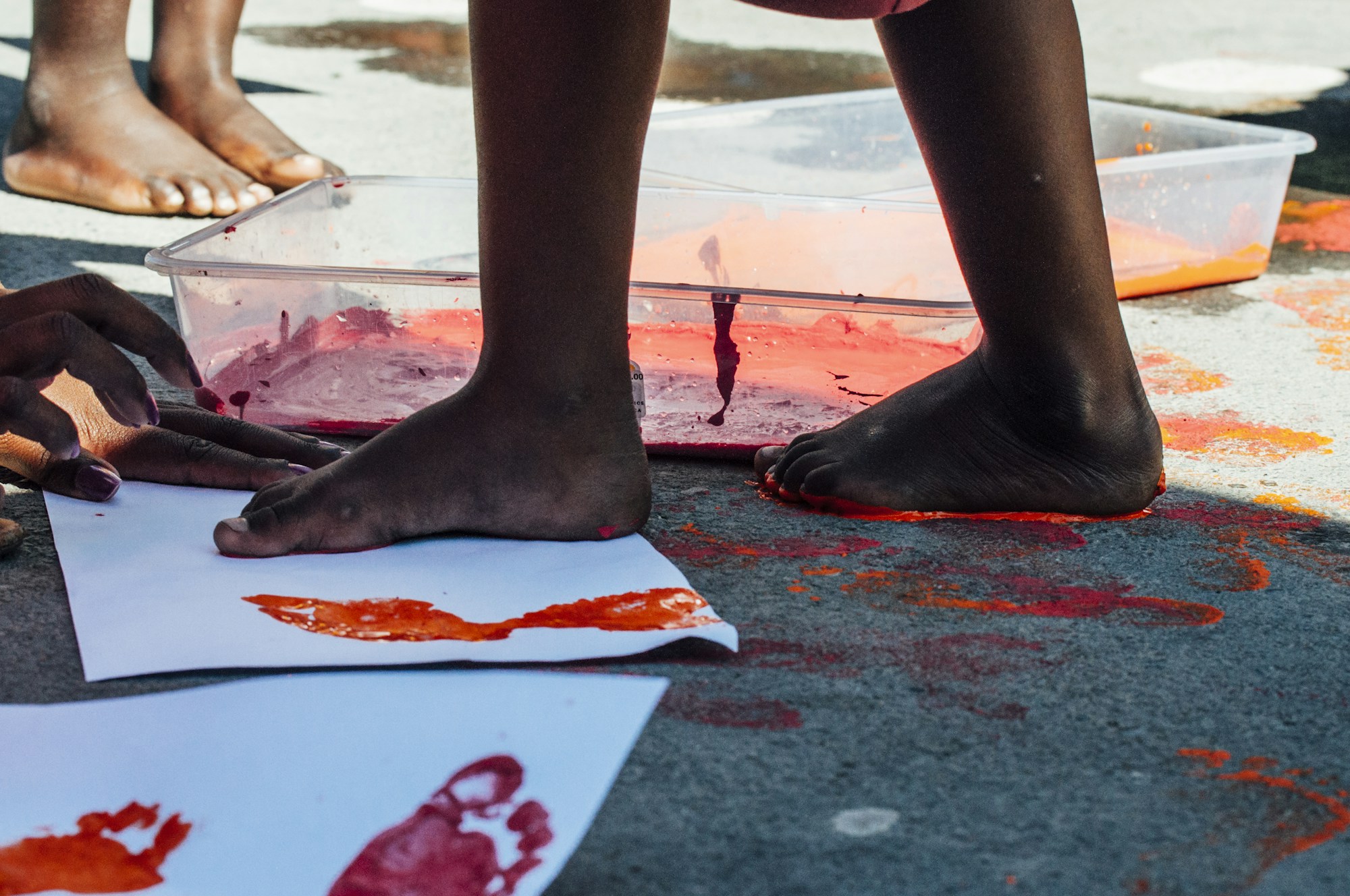 Kids stepping onto paper with painted feet during an outdoor footprint art session