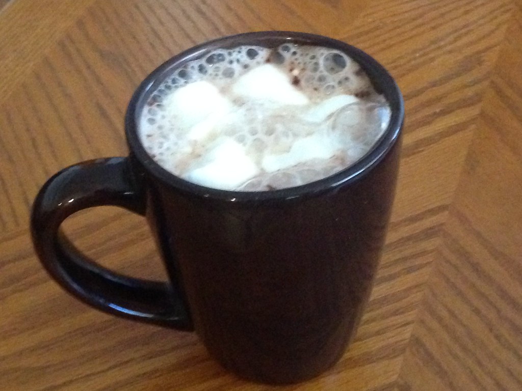 A mug of hot chocolate topped with marshmallows on a wooden table